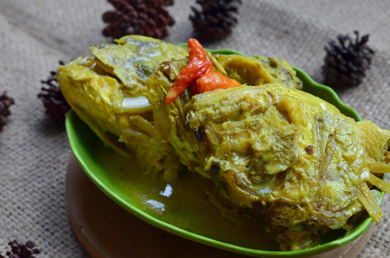 gulai kepala kakap eller snapper fisk huvud, kokta i curry krydda, den smakar kryddad, sur och välsmakande. traditionell padang kök, väst sumatra, Indonesien. foto