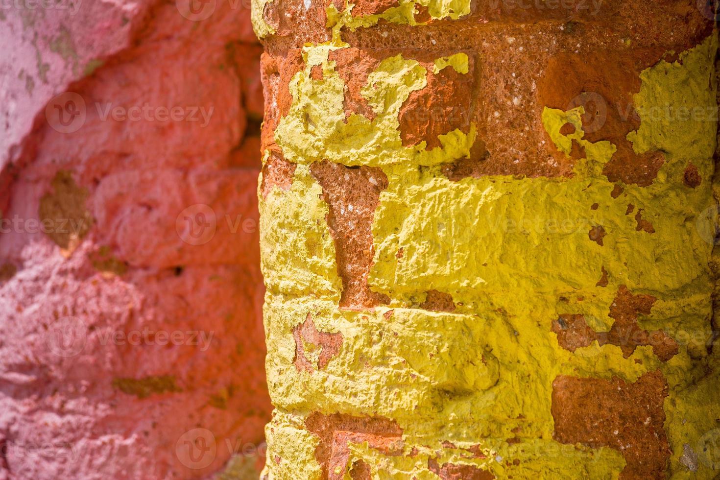 röd, orange, gul och blå Färg kombination gammal texturerad skada vägg med färgrik tegelstenar. foto