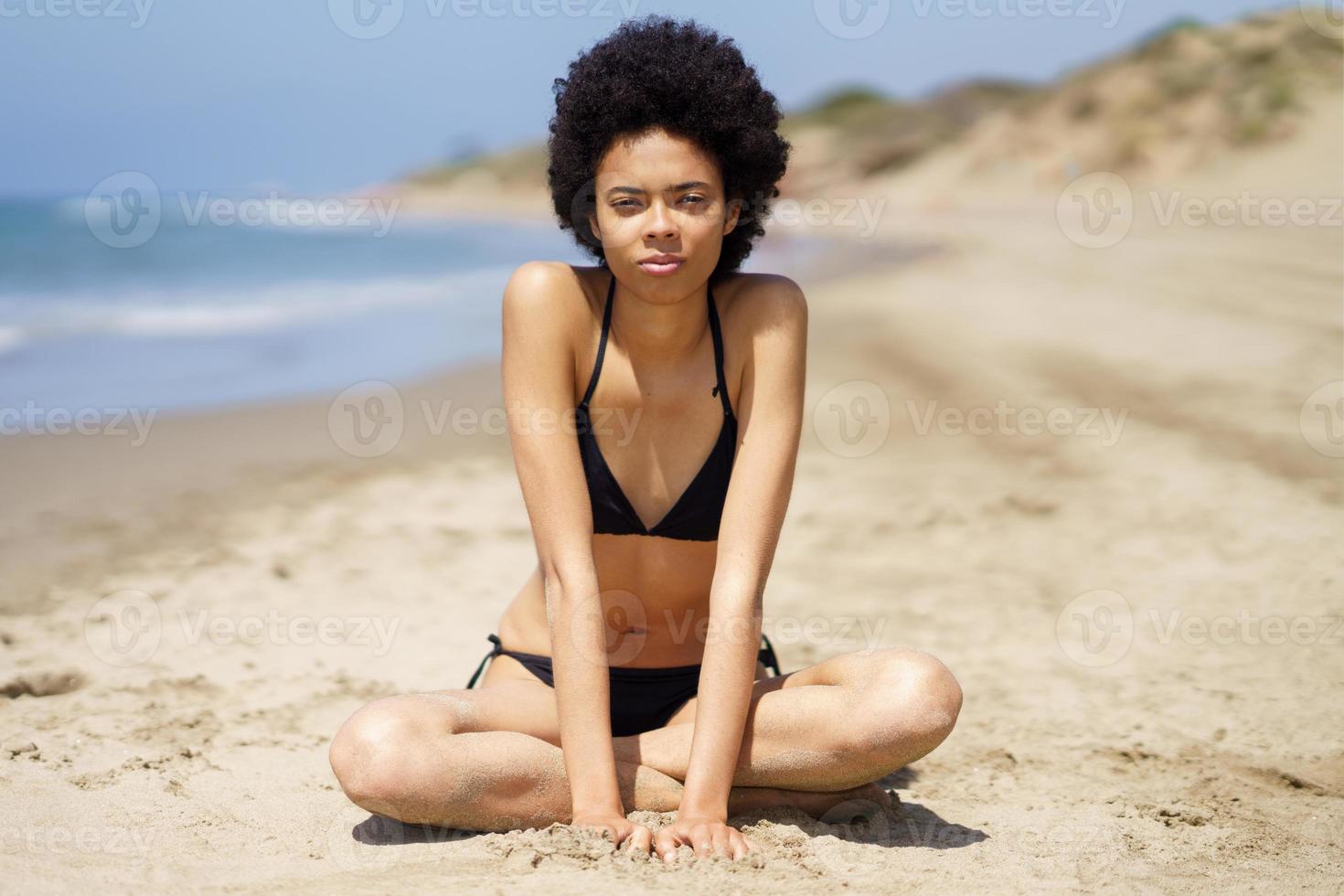 allvarlig svart kvinna med afro hår i bikini nära hav foto