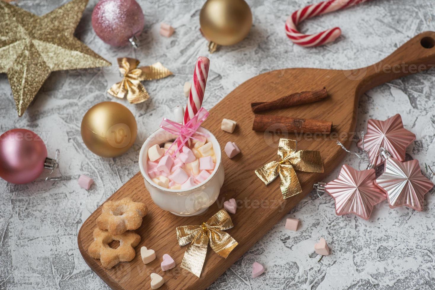 nyårs- eller julkompositionskopp med marshmelow på ett träställ med kakor och godis bland nyårs, glänsande leksaker foto
