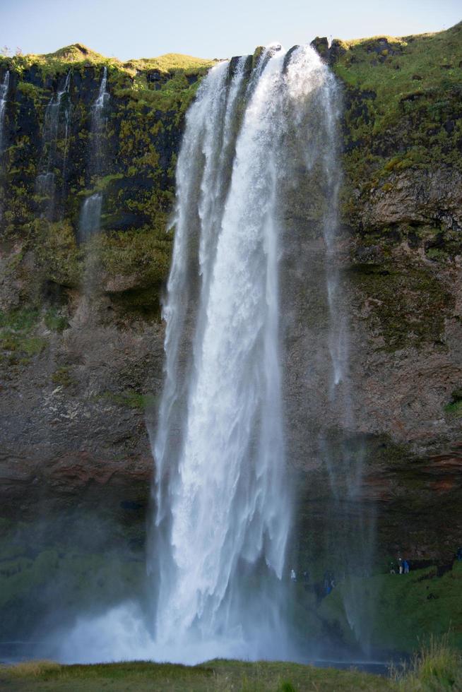 Seljalandsfoss klyfta, i island. tillfällig människor Bakom de vatten foto