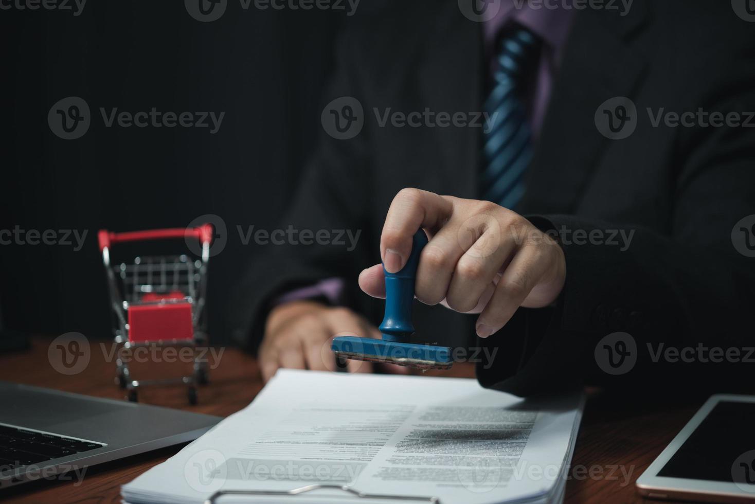 man hand stämpling godkännande signering på dokumentera eller pappersarbete kontrakt på skrivbord. foto