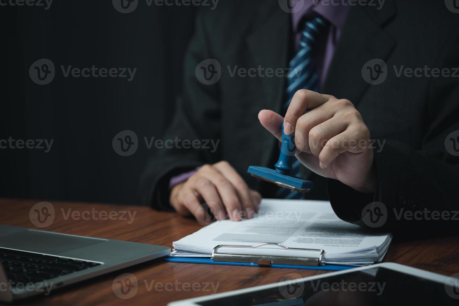 man hand stämpling godkännande signering på dokumentera eller pappersarbete kontrakt på skrivbord. foto