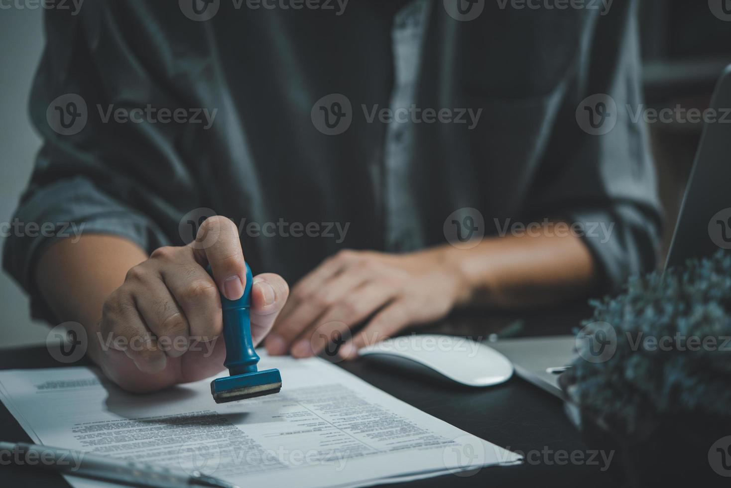 man hand stämpling godkännande signering på dokumentera eller pappersarbete kontrakt på skrivbord. foto