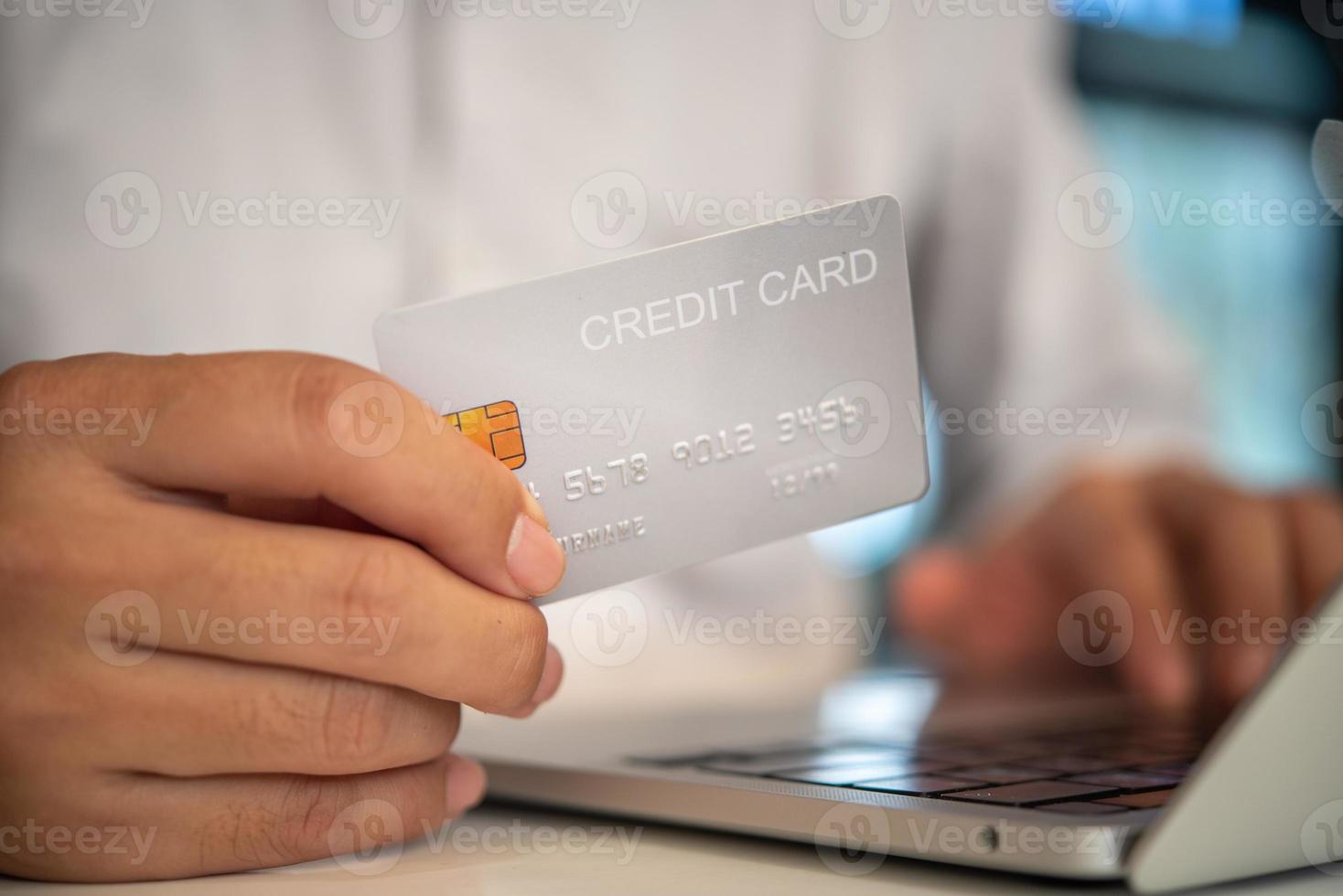 uppkopplad handla e-handel eller internet bank koncept.man hand innehav kreditera kort och använder sig av laptop.business finansiera betalning och bokföring. foto