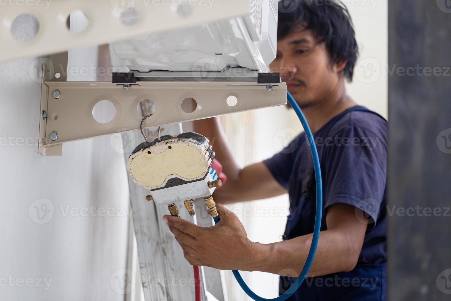 ung reparatör fixering luft balsam enhet, asiatisk tekniker man montera ett luft konditionering i en klient hus, underhåll och reparation begrepp foto