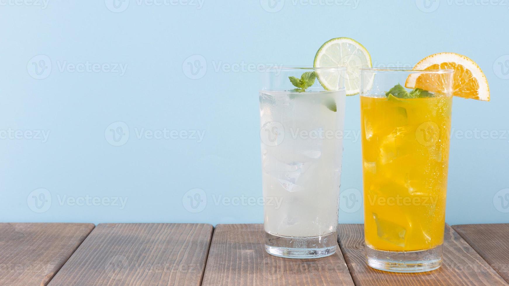 glas orange limonaddrink på träbord och blå bakgrund foto