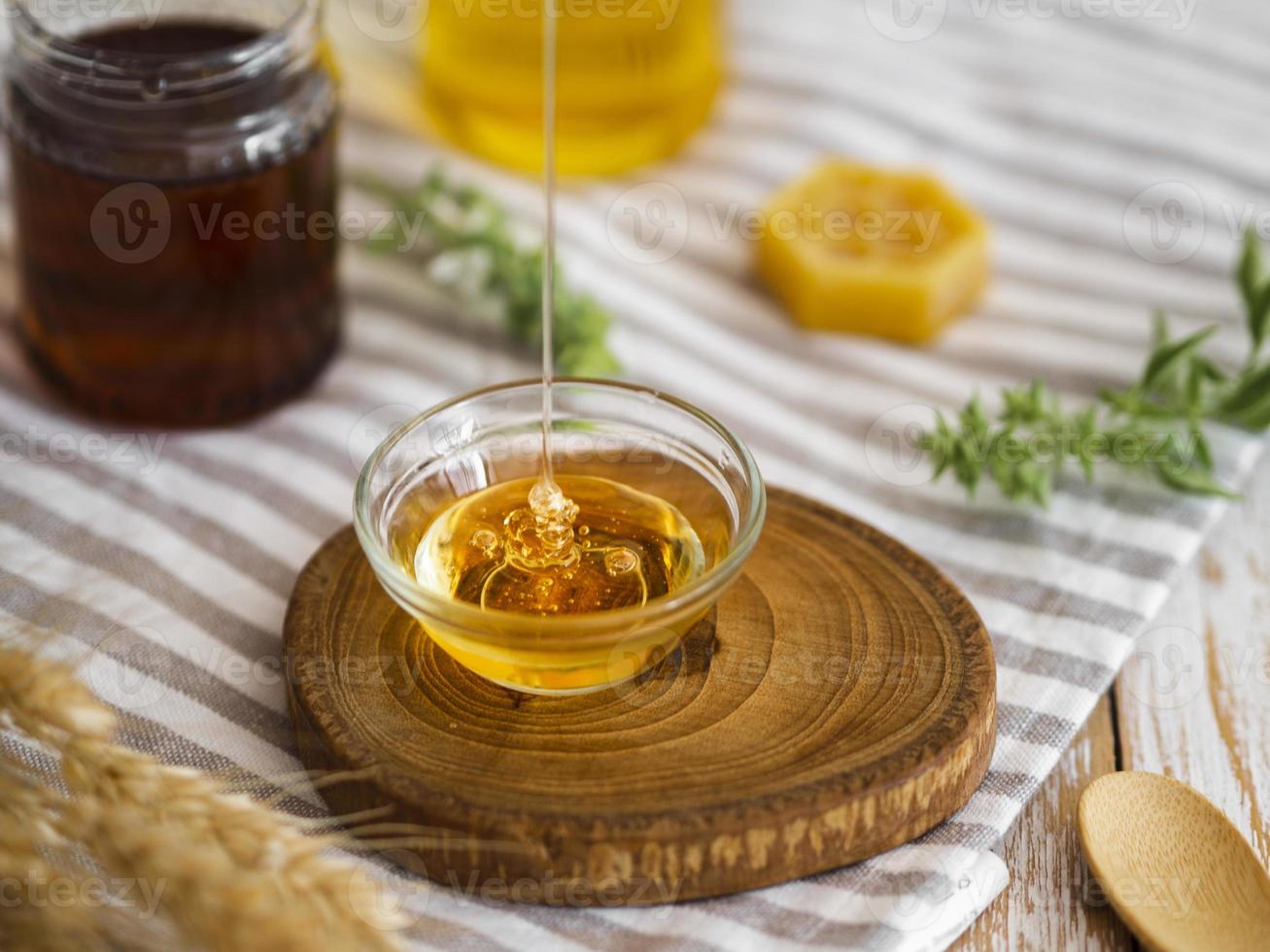 läcker honung som häller i glasskål, närbild foto
