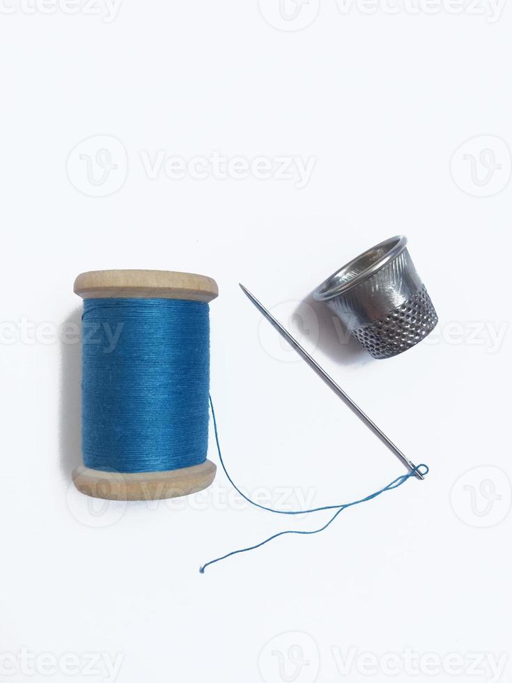 en spole av blå tråd, kaus och nål foto
