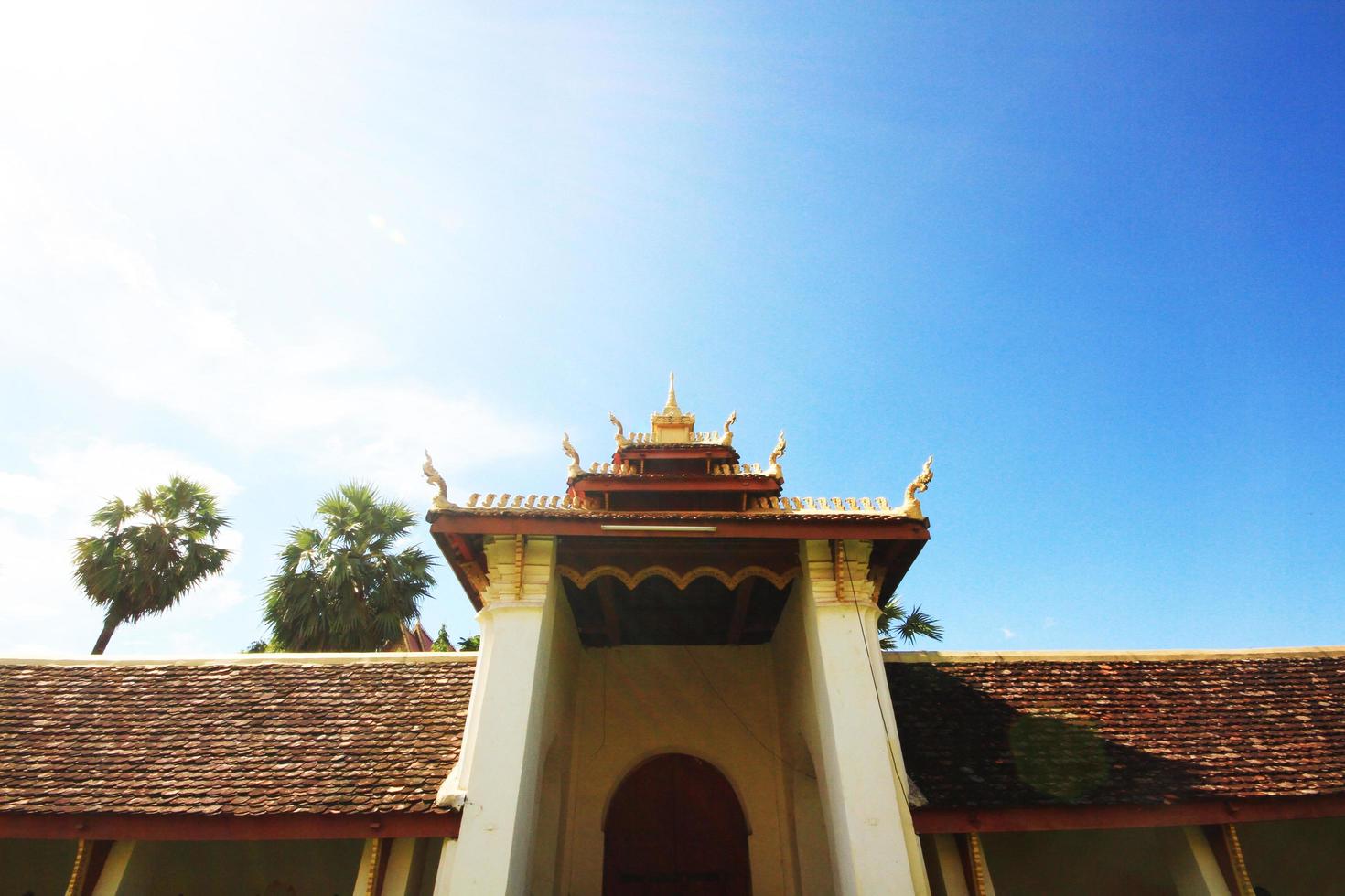 gyllene naga på konst tak av buddist tempel med blå himmel i wat pha den där luang tempel vientiane provins, laos foto