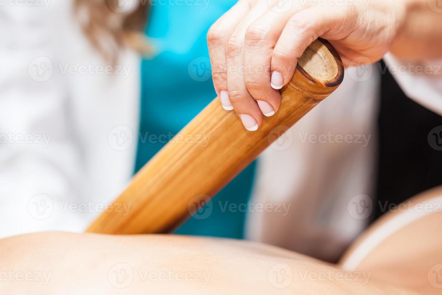 läkare utför en bambu terapi behandling på en ung kvinna patient tillbaka foto