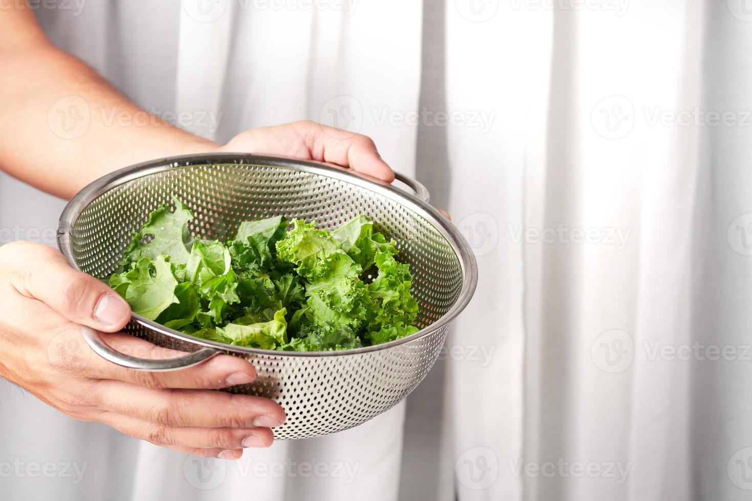 begrepp hand innehav en tvättning skål durkslag av färsk organisk grönkål. vit ridå bakgrund med kopia Plats foto
