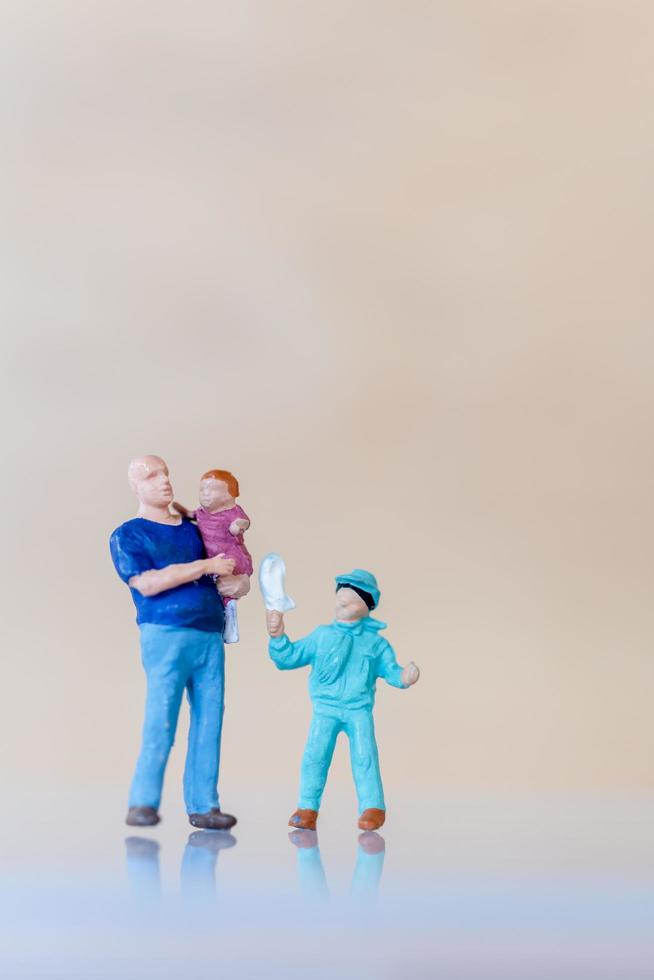 miniatyr människor, far håller sin söta baby dotter i armar med kopia utrymme för text, fars dag koncept foto