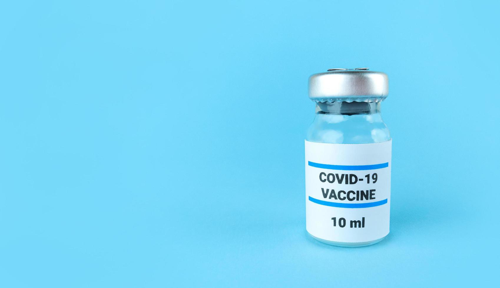 medicin flaska med covid-19 vaccin på en blå bakgrund med kopia utrymme. foto