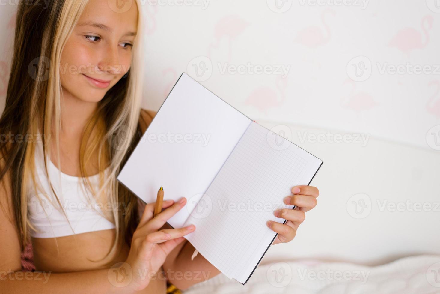 Tonårs flicka innehar en anteckningsbok eller dagbok i henne händer och visar dess sidor, en layout för kopia Plats foto