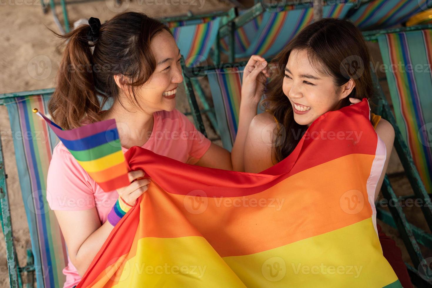 Lycklig lesbisk, skön asiatisk ung två kvinnor, flicka Gay, par kärlek ögonblick utgifterna Bra tid tillsammans, innehav de HBTQ flagga på de strand. lgbtq begrepp foto