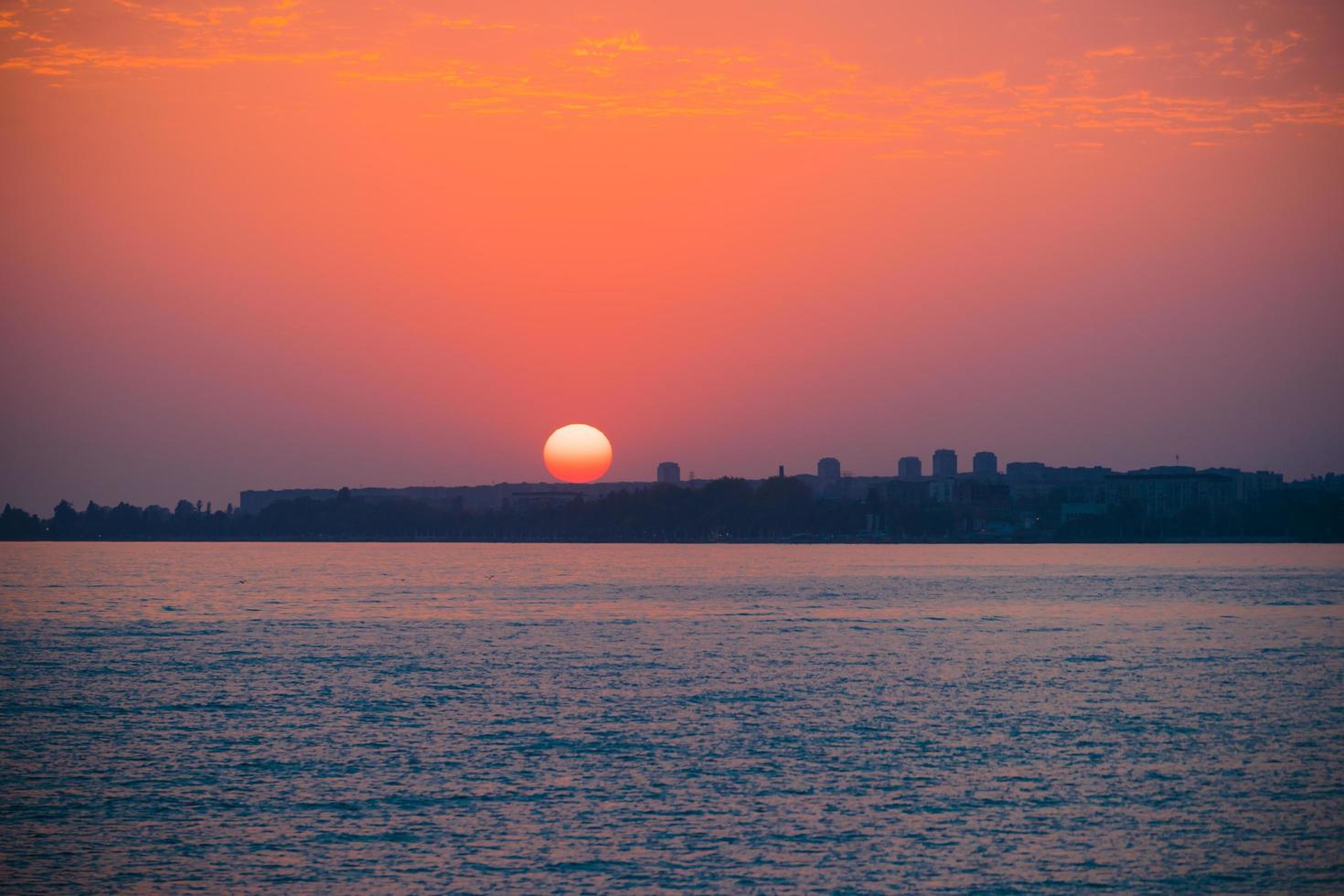 färgrik röd solnedgång över en vattenkropp och stadsbild i sukhumi, abkhasien foto