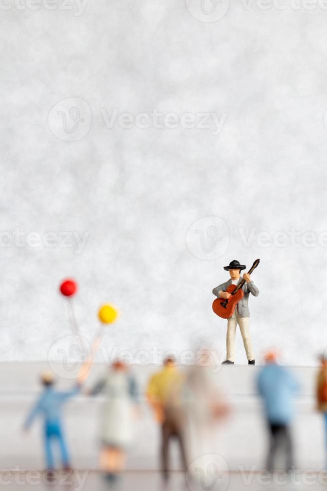 miniatyr- musiker spelar en gitarr på skede, värld musik dag begrepp foto