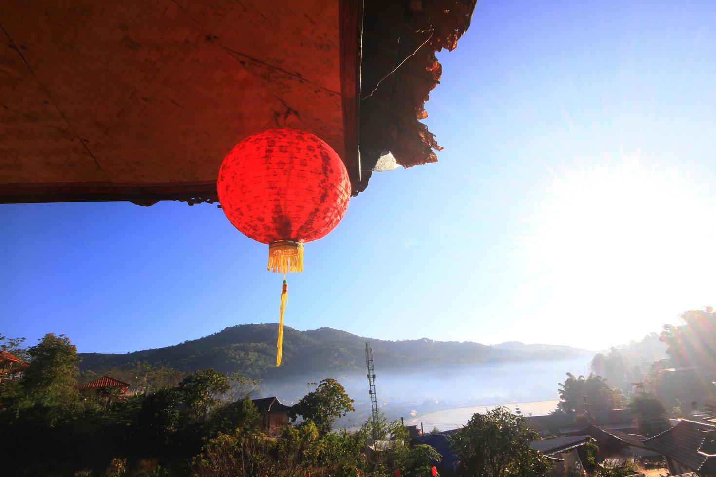 skön röd papper kinesisk lyktor ljus hängande och dekoration på takfot av kulle stam trä hus på de berg i thailand foto