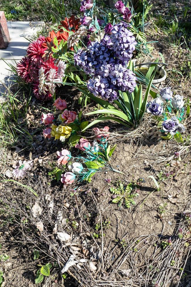 gammal artificiell blommor på grav mound i kyrkogård foto