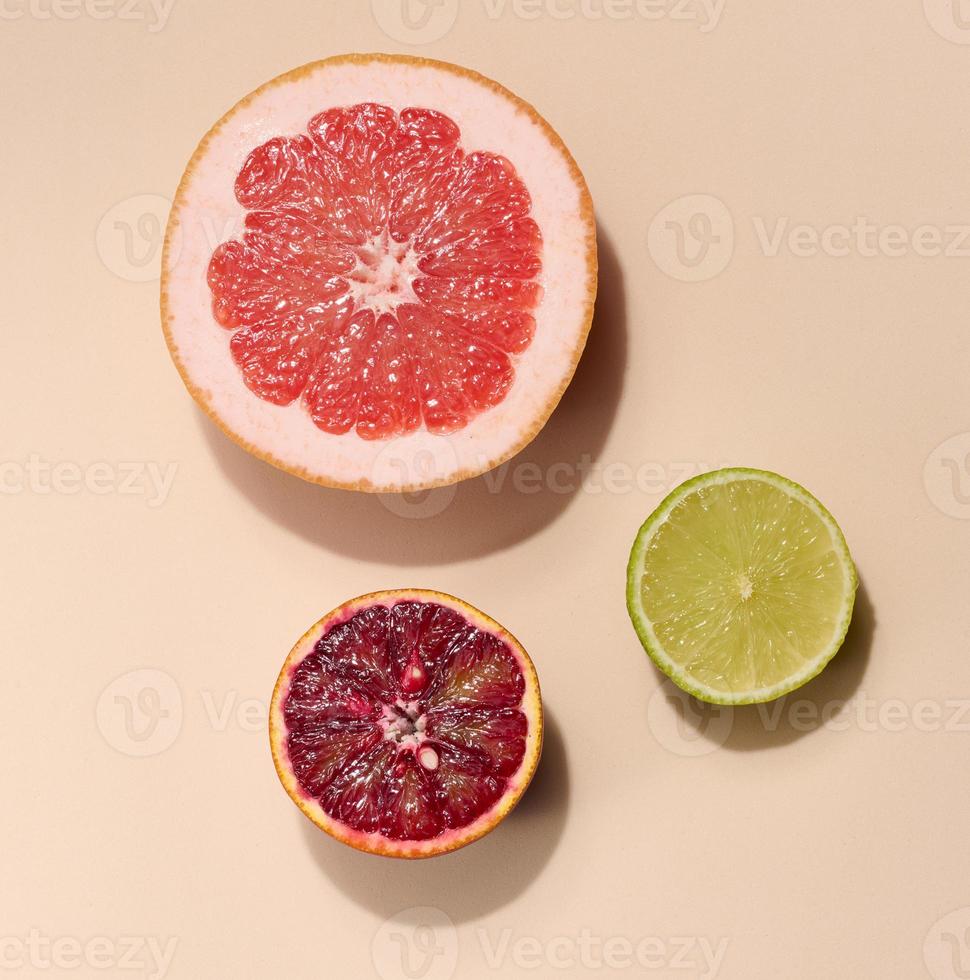 skivad bitar av orange, kalk och grapefrukt på en beige bakgrund, topp se foto
