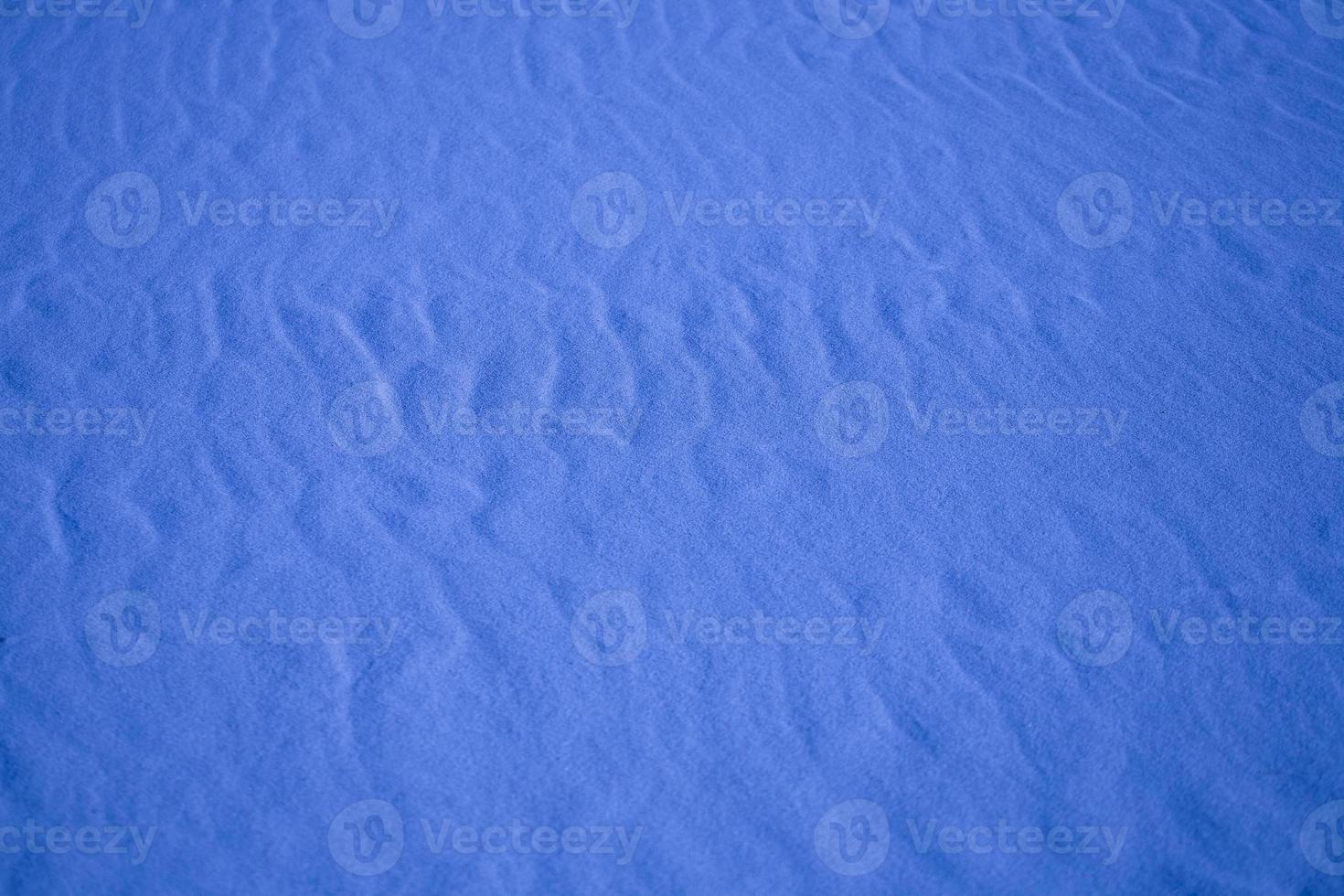 blå bakgrund med sand i de form av sand vågor foto