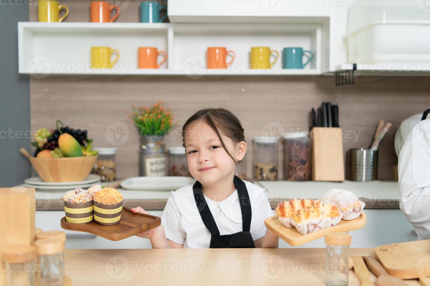 porträtt av en liten flicka i de kök av en hus har roligt spelar bakning bröd foto