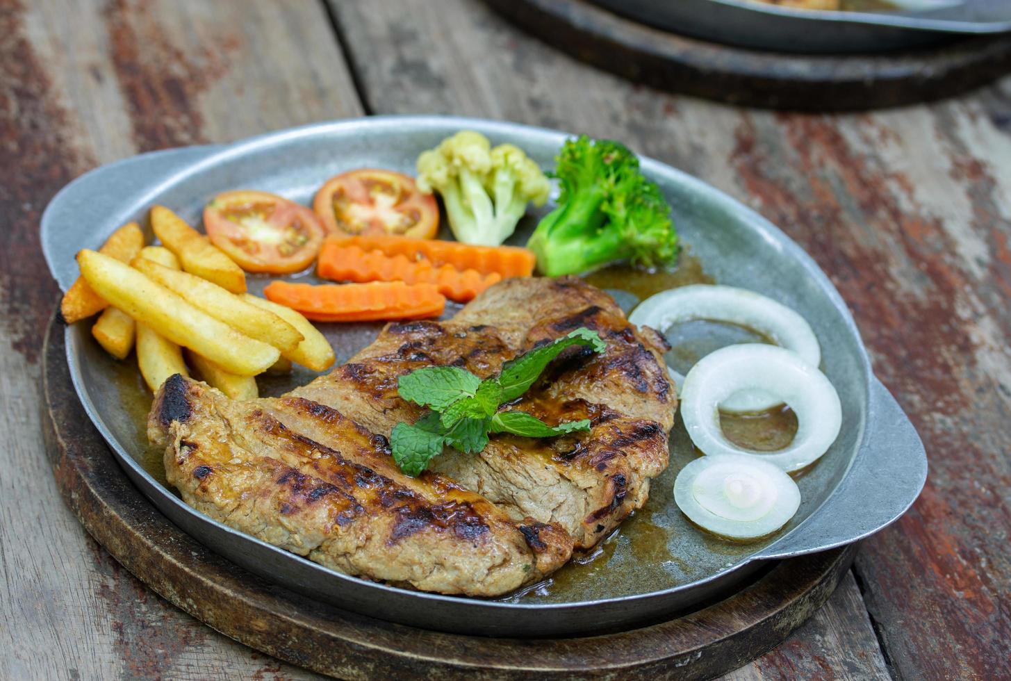 grillad fläsk biffar och franska frites med vegetabiliska foto