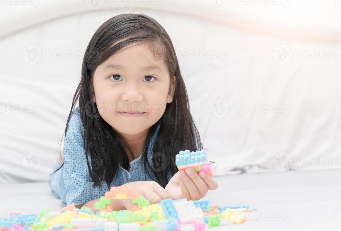 söt asiatisk flicka spela blockera tegelstenar på säng foto