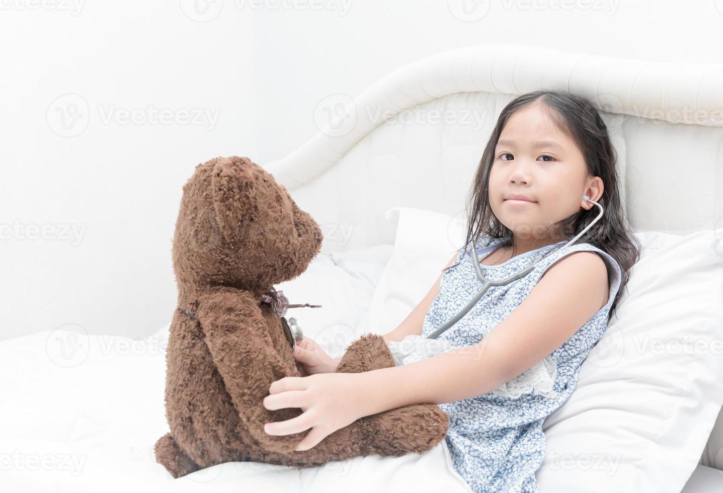 unge eller barn spelar läkare med stetoskop och teddy Björn foto