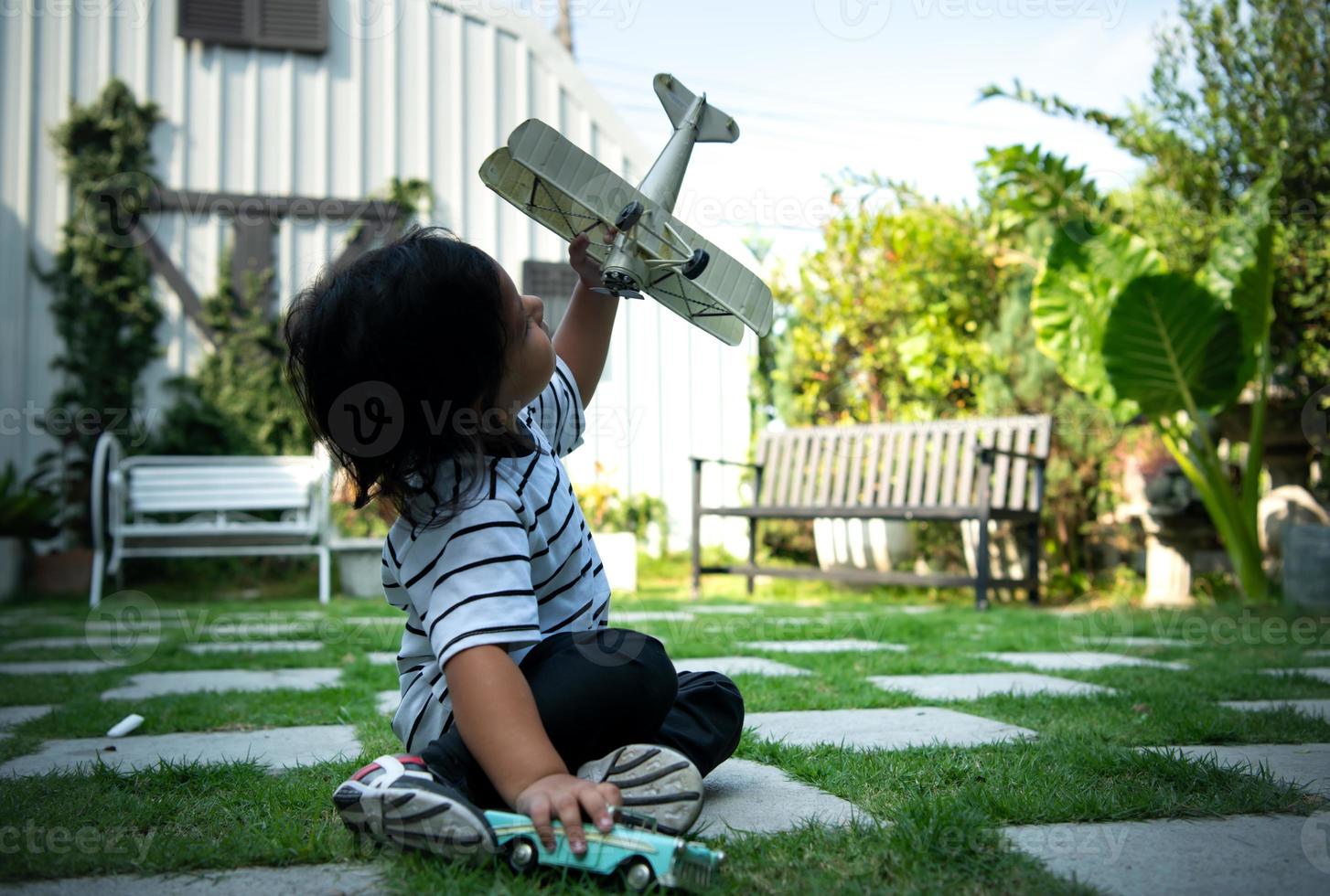 porträtt av en liten pojke i de främre gård. med modell flygplan som är de dröm av en barn vem vill ha till vara en pilot. foto