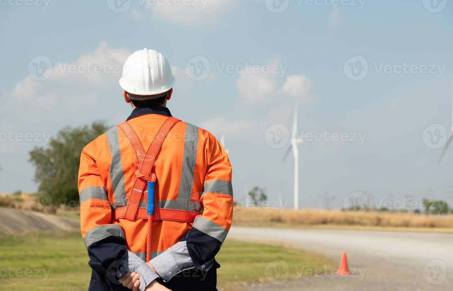 ingenjör på naturlig energi vind turbin webbplats med en uppdrag till ta vård av stor vind turbiner använda sig av en walkie prat till kommunicera med en kollega arbetssätt på topp av de vind turbin. foto