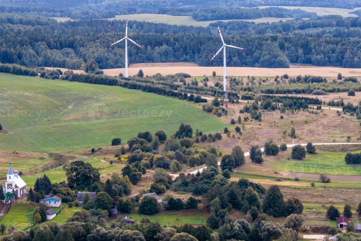 antenn panorama- se av grön by med hus, lador och grus väg i skog med väderkvarnar foto