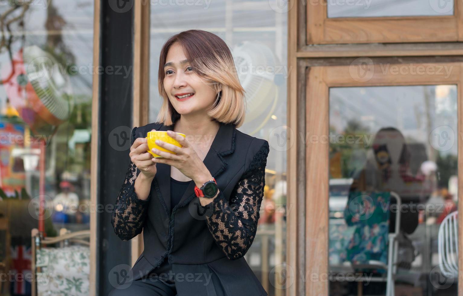 skön asiatisk kvinna Sammanträde utomhus- på en kaffe affär Kafé hand innehav kaffe kopp och leende med Lycklig känslor, livsstil avkopplande tid begrepp. foto