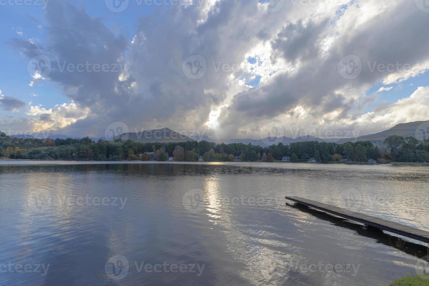 trä- brygga in i de sjö med moln ovan foto