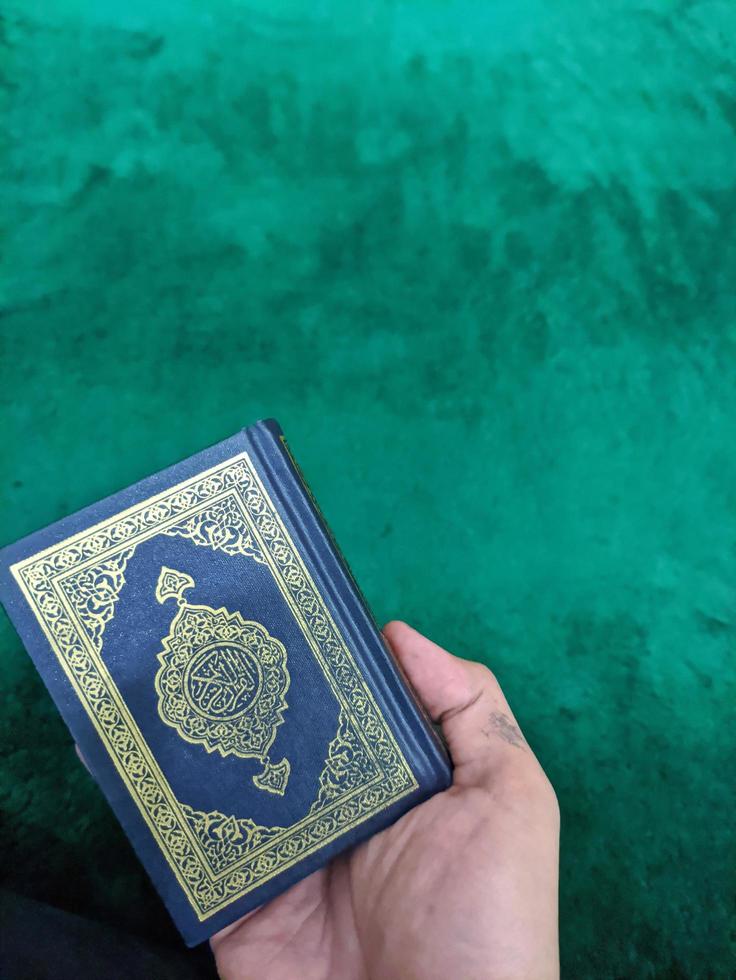 en Foto av man hand innehav en helig qur'an med grön bakgrund för kopia Plats, hand innehav en quran bok isolerat för kopia Plats