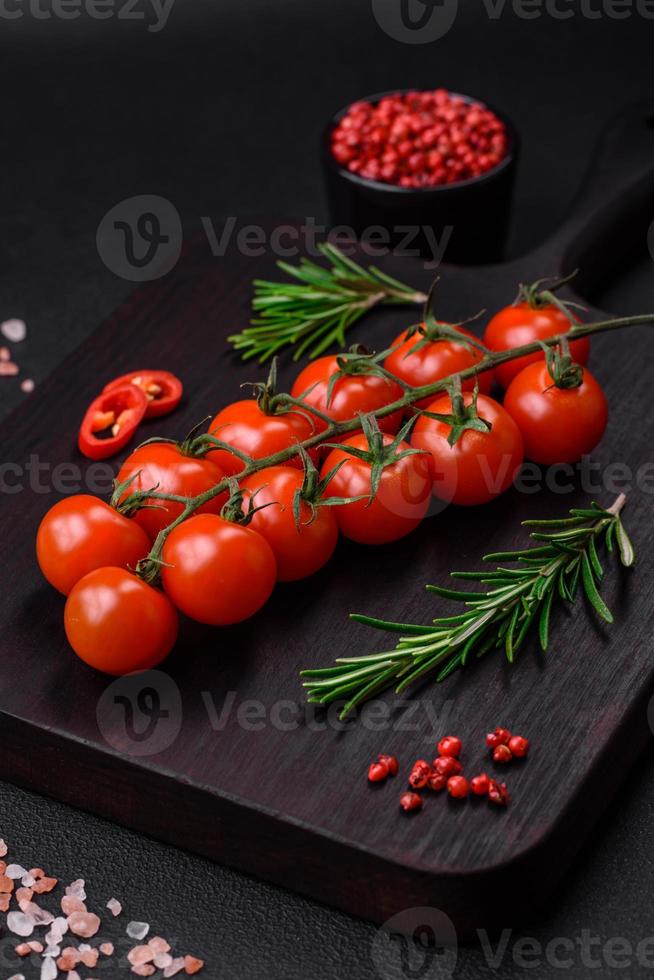 utsökt färsk körsbär tomater på en kvist på en mörk betong bakgrund foto