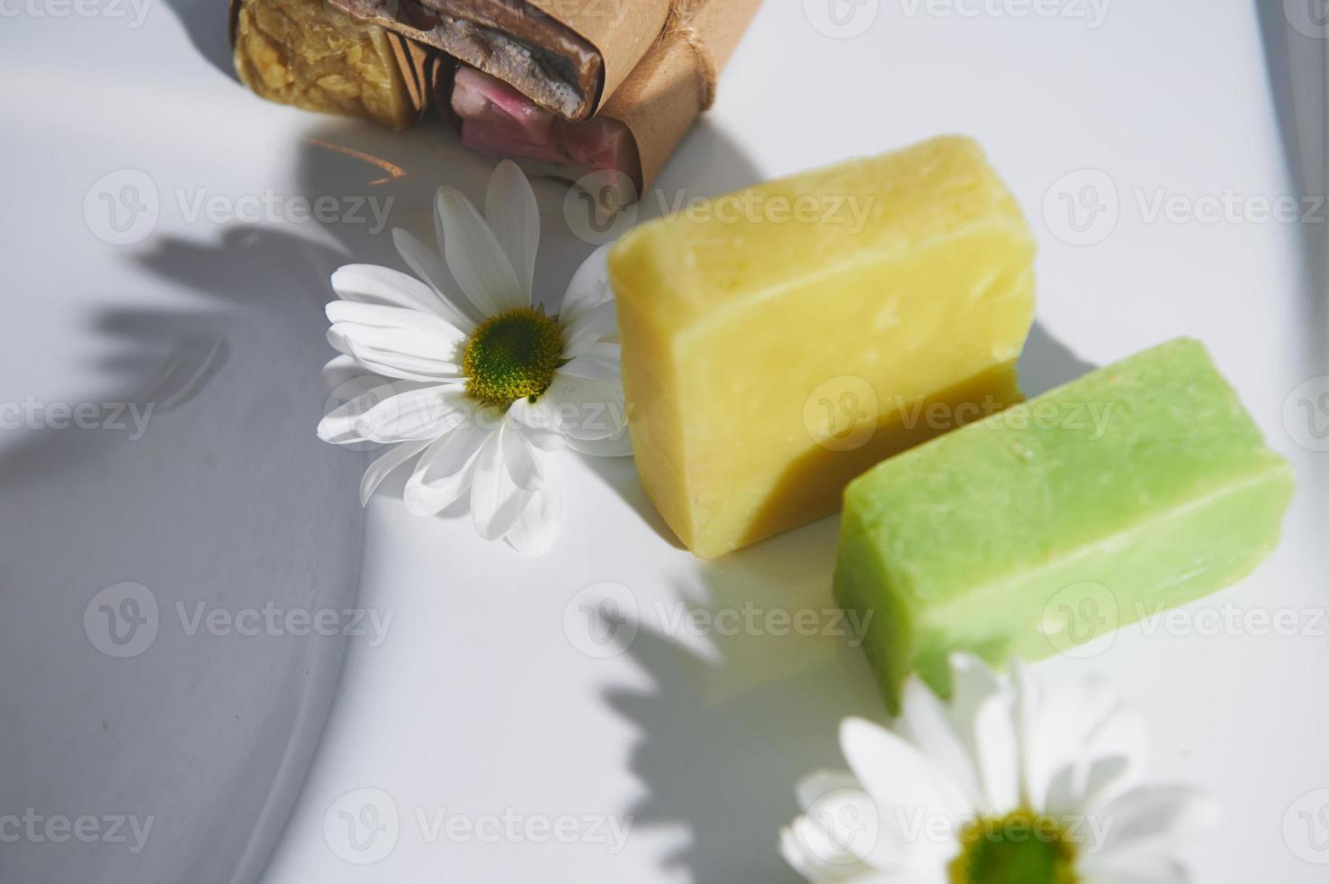 handgjort organisk eco tvål med naturlig Ingredienser av oliv olja och kamomill på vit keramisk tvättställ foto