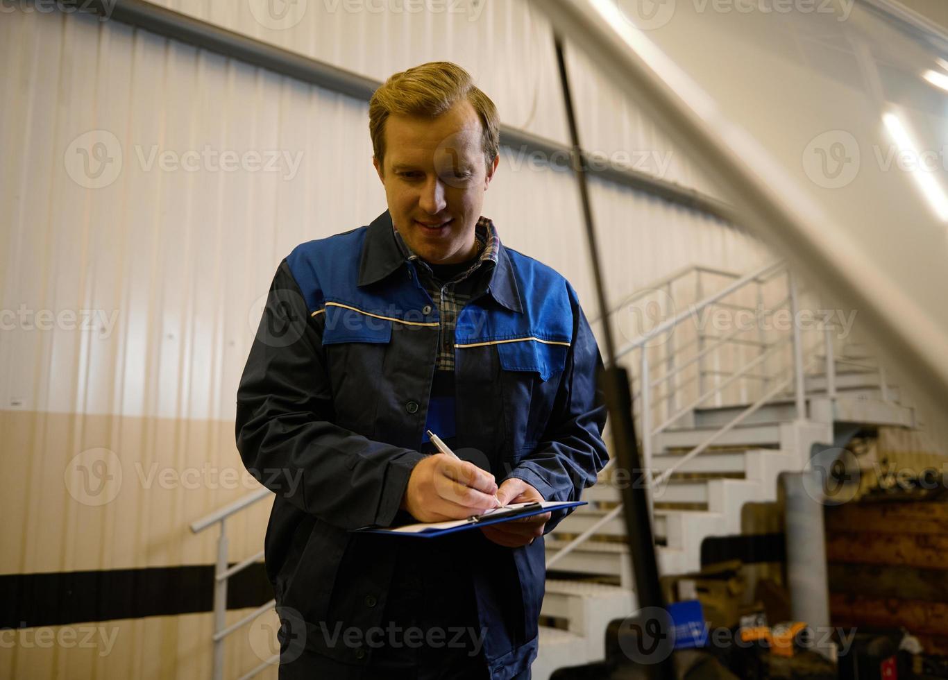 porträtt av bil mekaniker, tekniker, bil ingenjör i enhetlig framställning de checklista på Urklipp för reparation bil i de reparera affär under garanti bil underhåll. foto