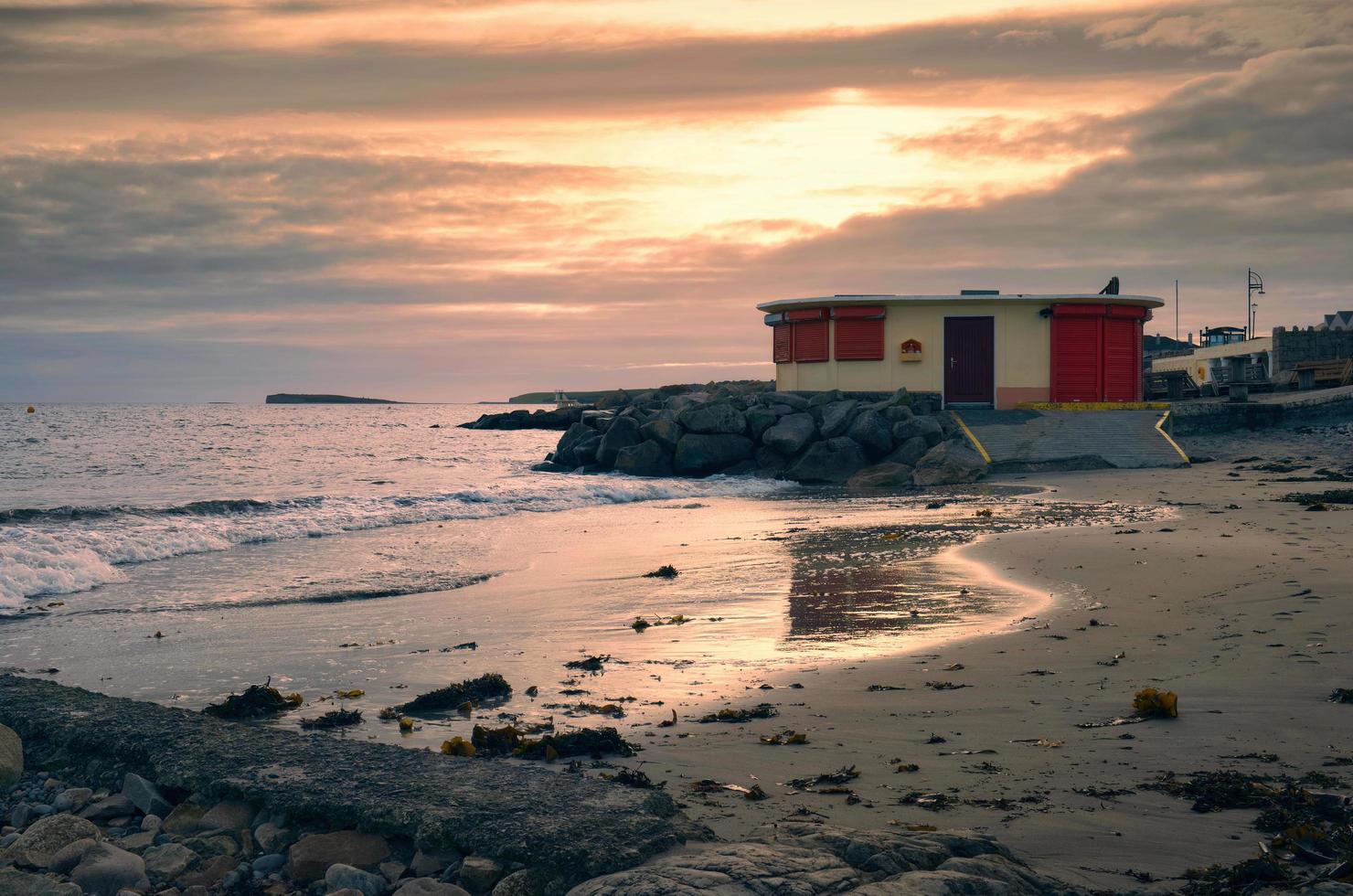 skön solnedgång kust landskap med strand hus på sandig salthill strand i galway, irland foto