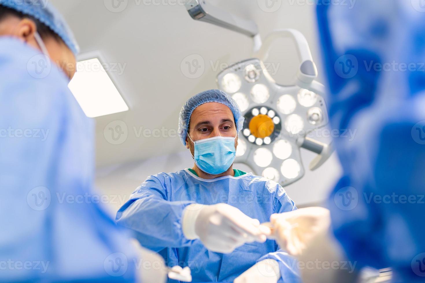 skott i de rörelse rum, assistent händer ut instrument till kirurger under drift. kirurger prestera drift. professionell medicinsk doktorer utför kirurgi. foto