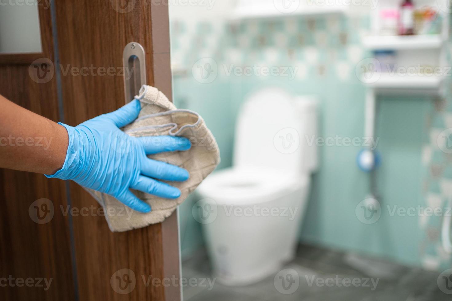 hembiträde rengöring en dörr hantera på toalett med alkohol och mjuk trasa på Hem. foto