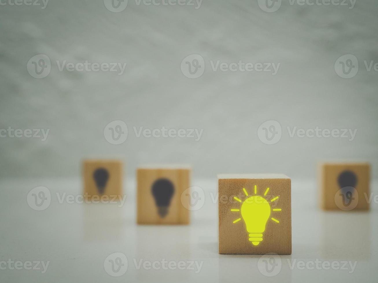 idéer och kreativitet trä- kub med ljus Glödlampa ikon på mörk bakgrund med ljus lökar. skapande ny idéer en annorlunda begrepp foto