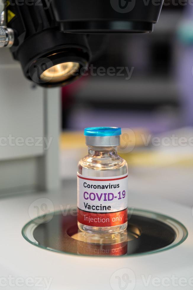 covid-19 vaccinflaska med mikroskop i laboratoriet foto