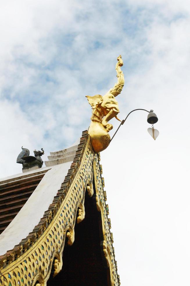 gyllene naga och klockorna hängande på konst tak av buddist tempel med blå himmel i thailand foto