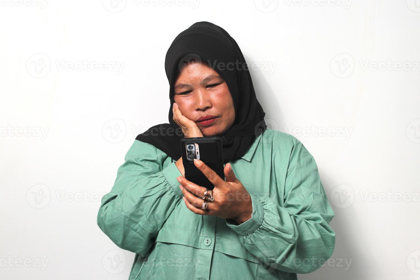 mitten åldrig asiatisk kvinnor bär hijab ser på henne telefon Galleri missar henne barn foto