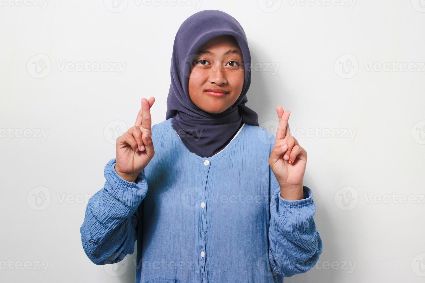 ung asiatisk flicka i hijab innehav fingrar korsade foto