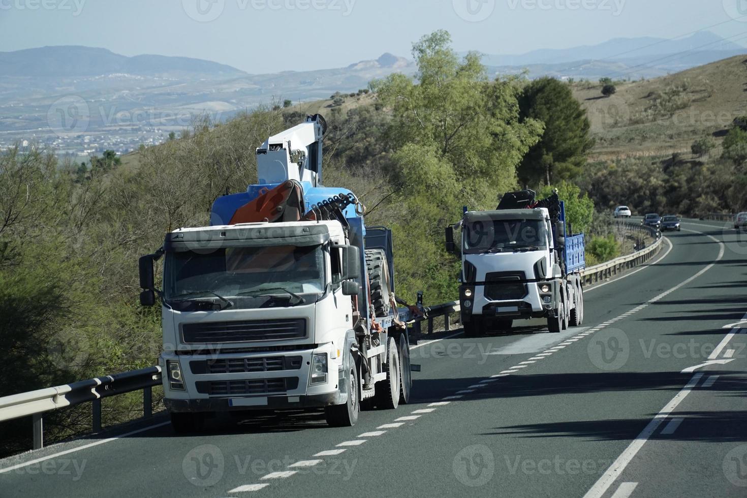två lastbilar med konstruktion Utrustning på en väg - främre se foto