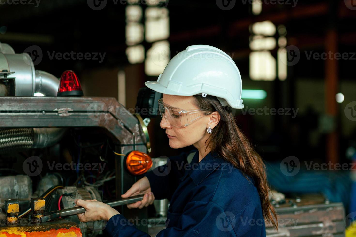 en Lycklig ung kvinna arbetstagare av en stor maskineri underhåll fabrik i en blå klänning och en vit skyddande hatt. underhåll underhåll. fabrik säkerhet. baner bild foto