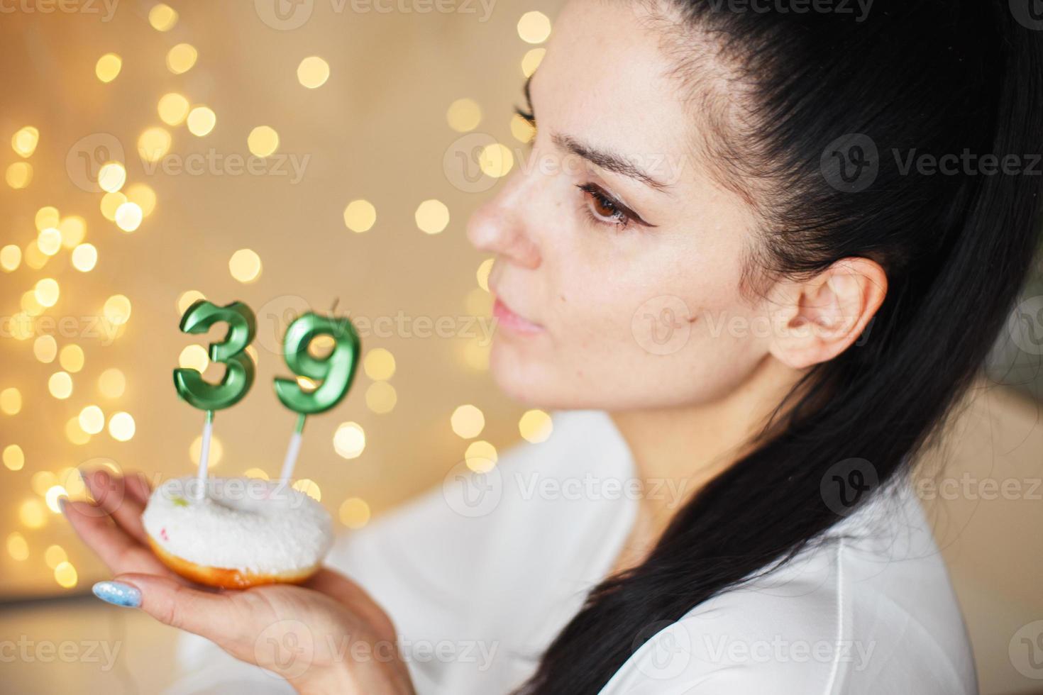 kvinna innehav en kaka med de siffra 39 ljus på festlig suddig bokeh bakgrund foto